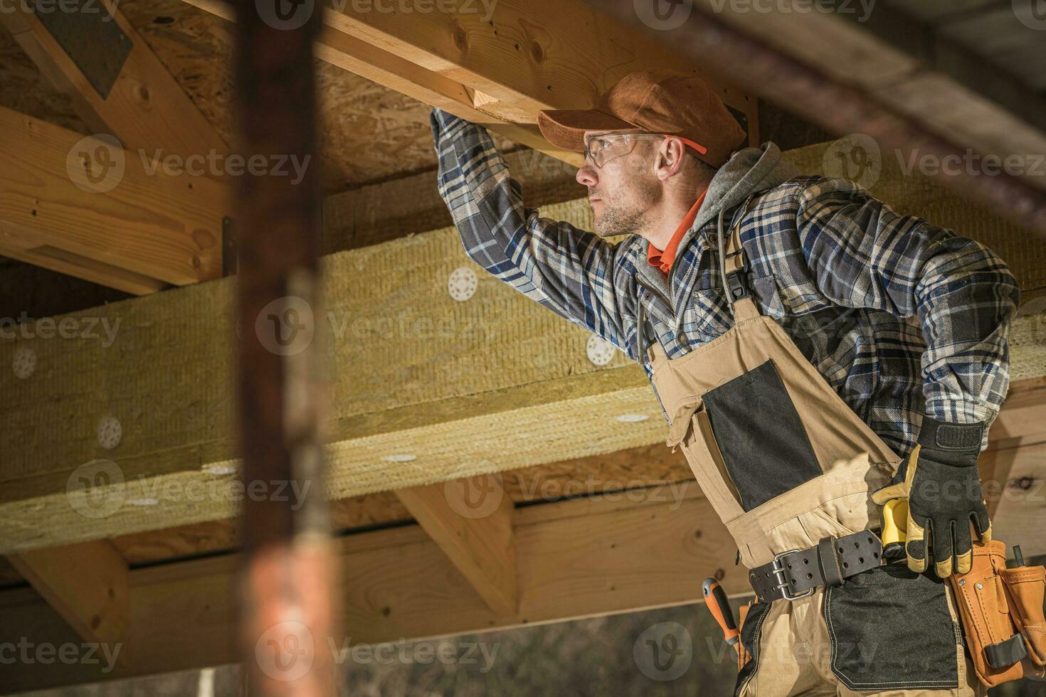 kaukasisch Arbeiter prüft hölzern Rahmung von Neu Dachgeschoß. foto