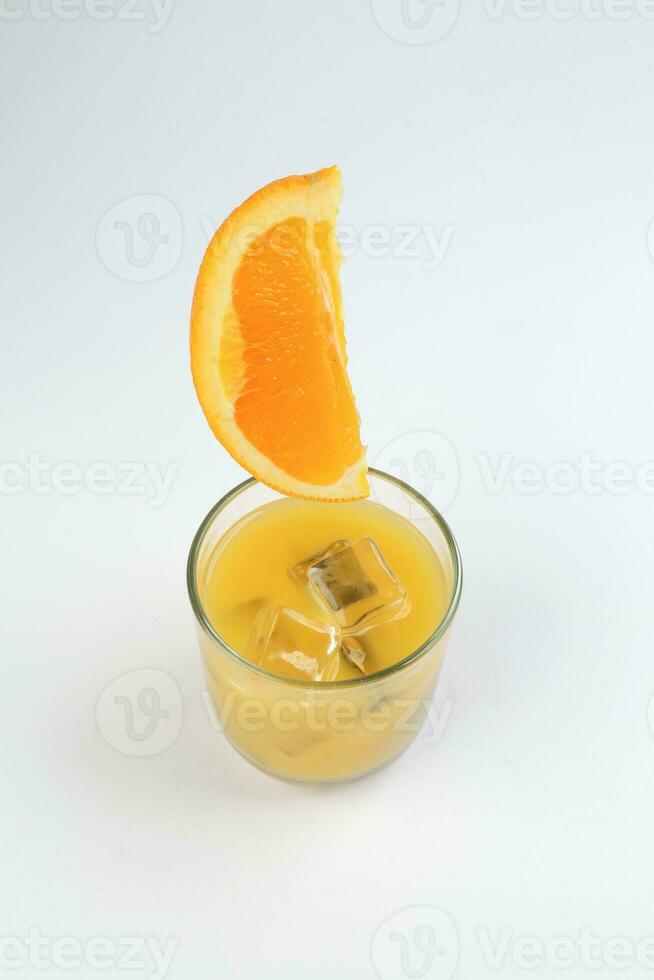 frisch Gelb Orange Saft im Glas mit ganze schwebend geschnitten Orange Obst und Eis Würfel auf Weiß Hintergrund foto