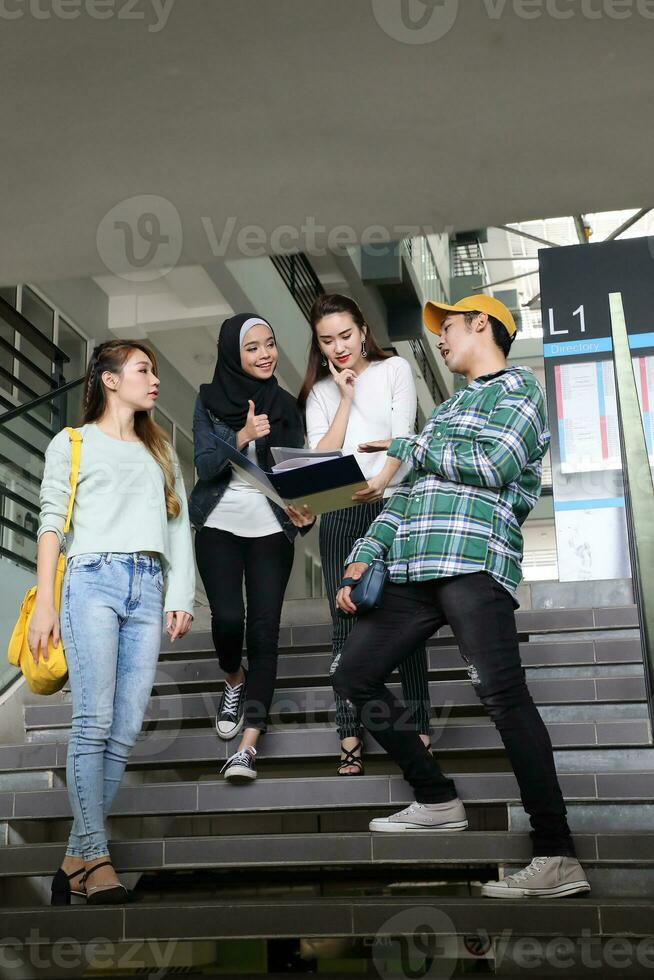jung asiatisch malaiisch Chinesisch Mann Frau Innen- Treppe Gang Campus Buch Datei Mappe Laptop Computer Telefon sitzen Stand Studie mischen foto
