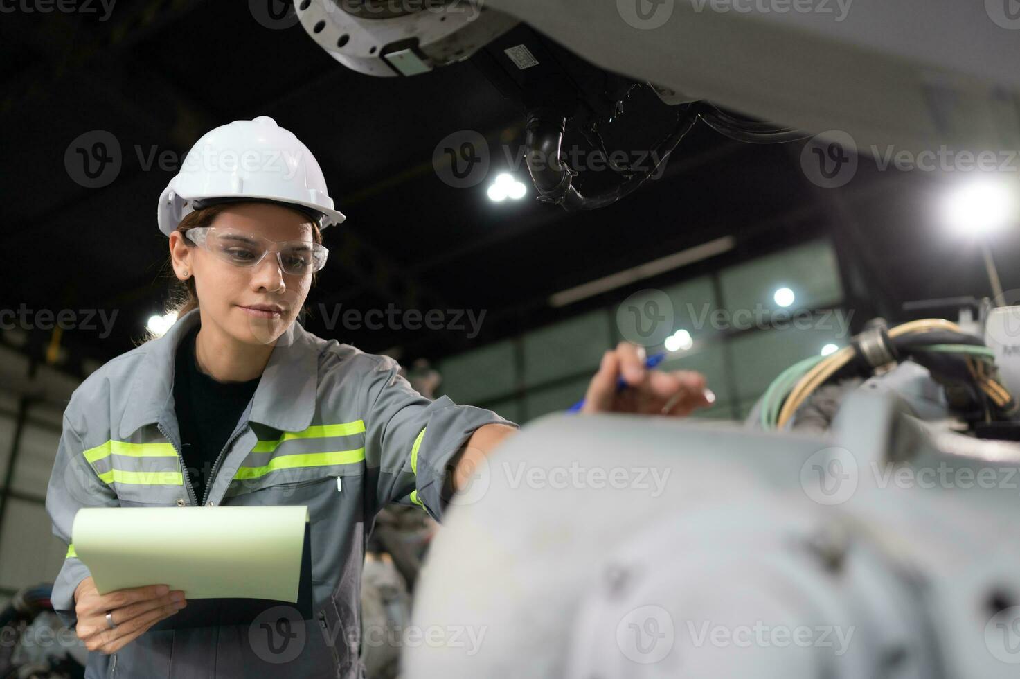 ein weiblich Ingenieur Überprüfung dokumentiert Artikel nach Installation ein Programm auf ein Roboter Arm im ein Roboter Warenhaus und Prüfung das Betrieb foto