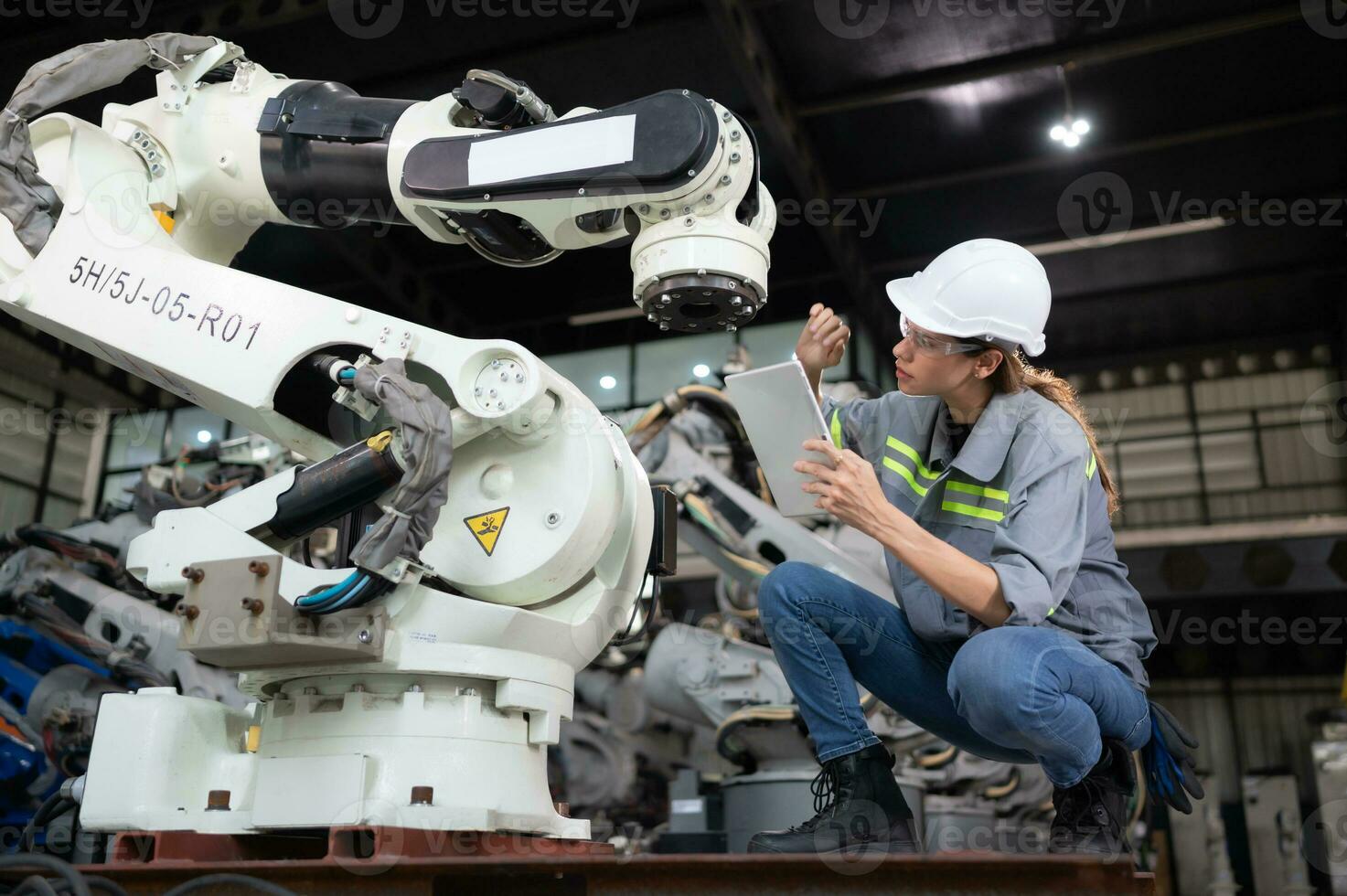 ein weiblich Ingenieur installiert ein Programm auf ein Robotik Arm im ein Roboter Lagerhaus. und Prüfung das Betrieb Vor Senden das Maschine zu das Kunde. foto