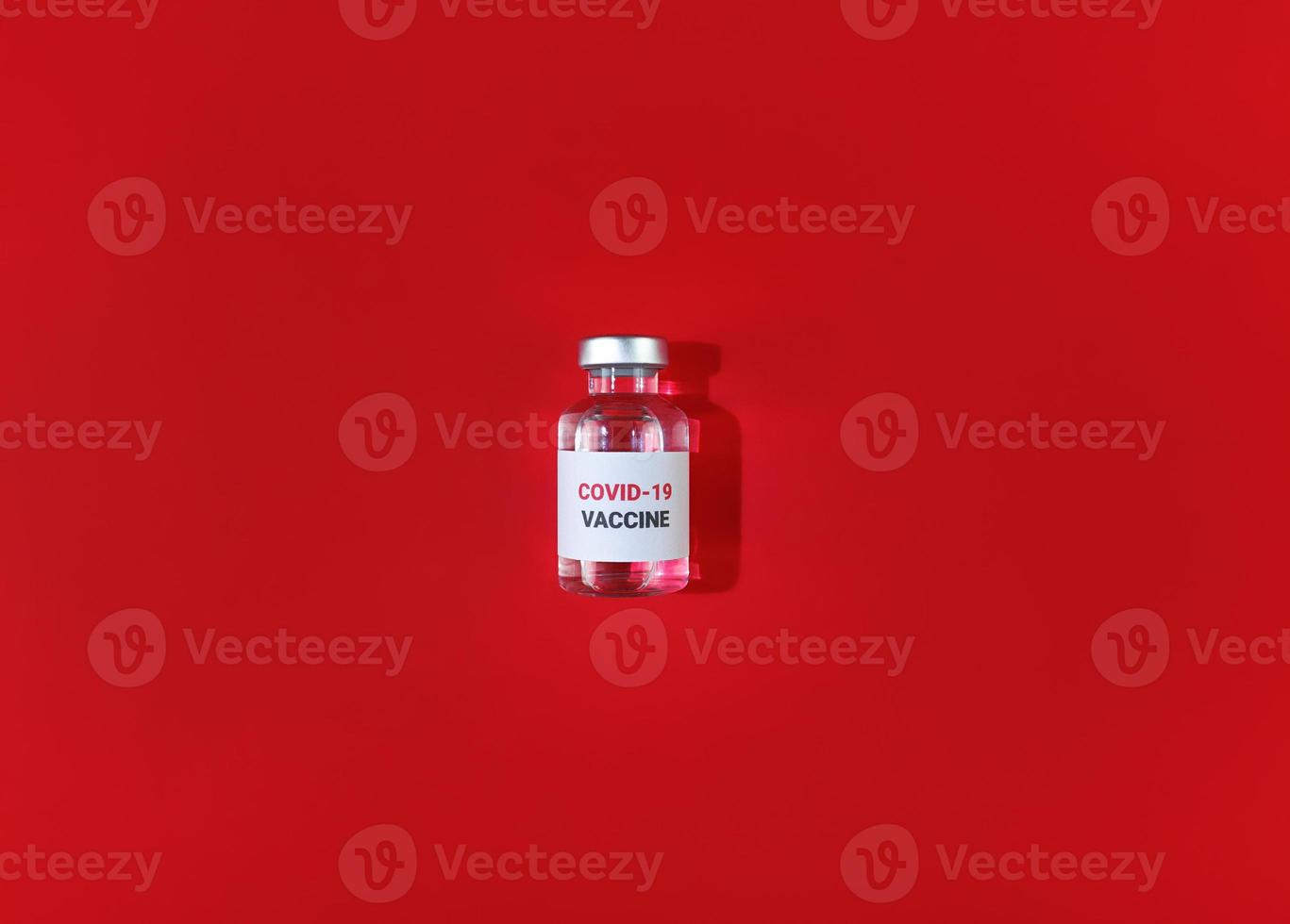 Fläschchen mit Covid 19 Impfstoff auf rotem Hintergrund medizinische einfache flache Lage foto