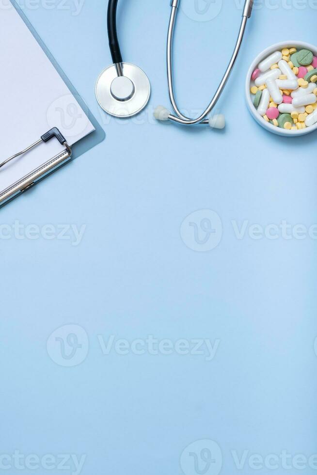 Fragment von Stethoskop, Tablette, Tabletten auf Blau Hintergrund mit Kopieren Raum. Gesundheitswesen und Medizin Konzept eben legen, oben Aussicht foto