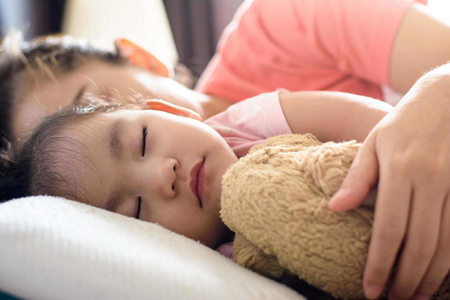 Nahaufnahme niedlichen asiatischen Baby und ihre Mutter schlafen auf dem Bett foto