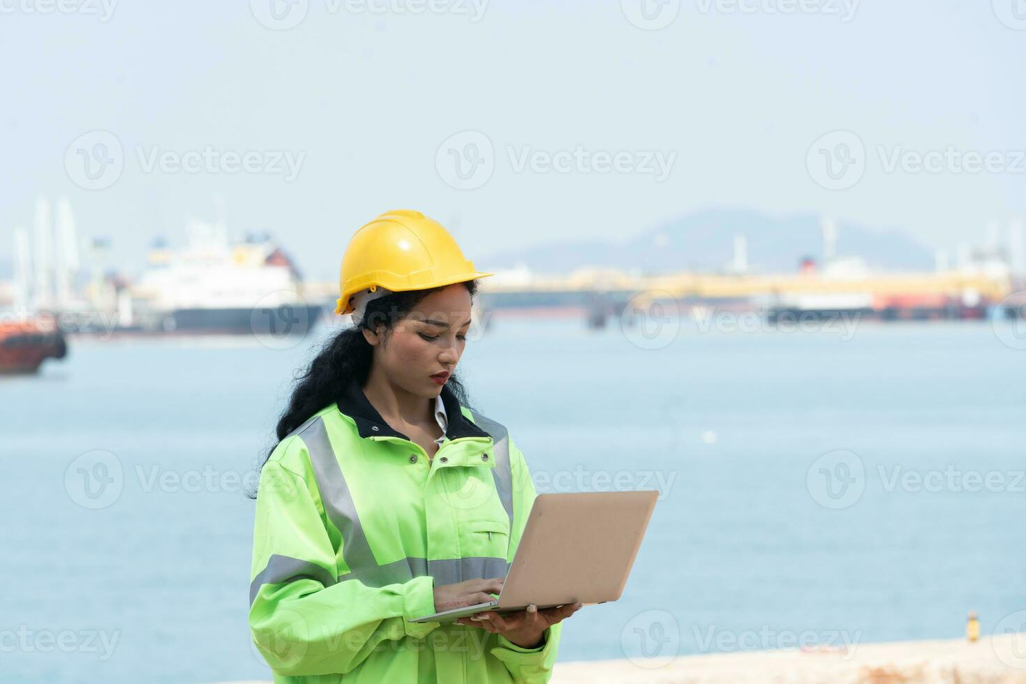 asiatisch weiblich Ingenieur halten Laptop mit Ozean Schiff Hintergrund foto