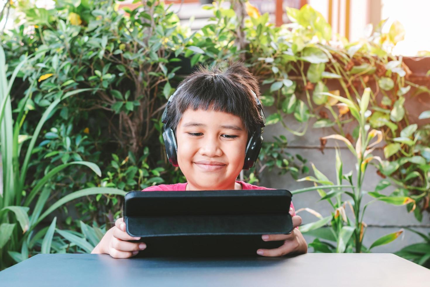asiatischer süßer Junge, der Spiele auf dem Tablett spielt foto