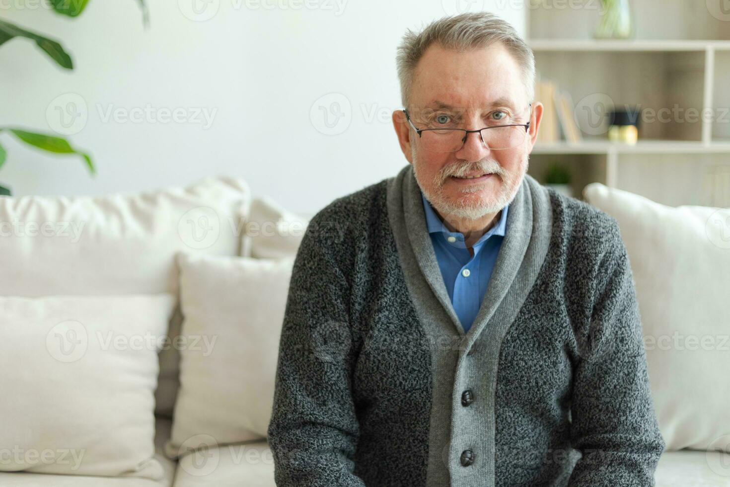 zuversichtlich stilvoll Mitte alt Senior Mann beim heim. älter reifen 70er Jahre Mann lächelnd. glücklich attraktiv Senior Bart Großvater suchen Kamera schließen oben Gesicht Kopfschuss Porträt. glücklich Personen. foto