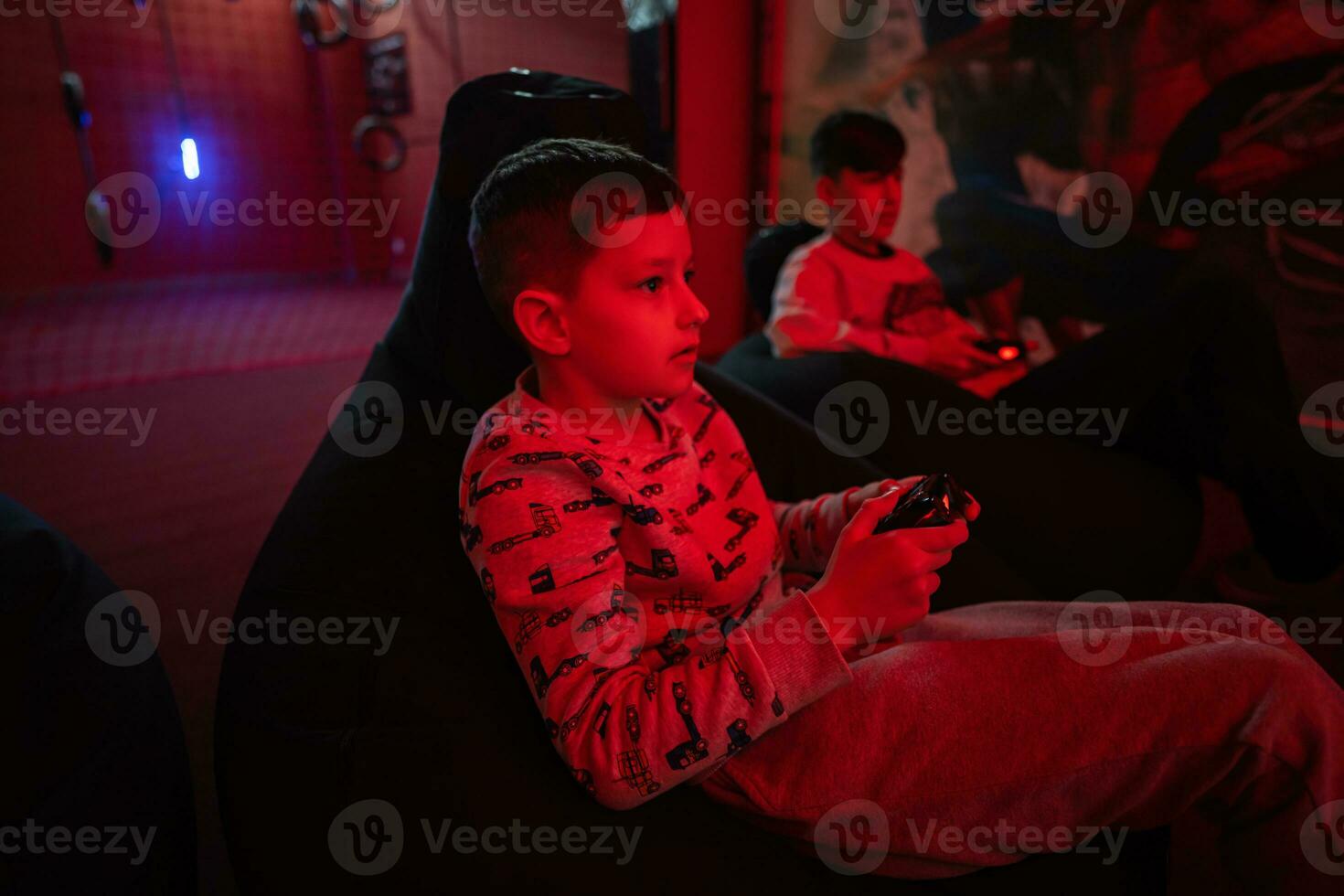 zwei Jungs Spieler abspielen Gamepad Video Spiel Konsole im rot Spielen Zimmer. foto