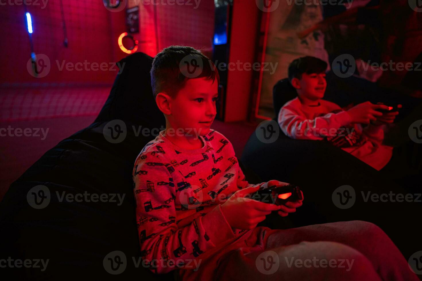 zwei Jungs Spieler abspielen Gamepad Video Spiel Konsole im rot Spielen Zimmer. foto