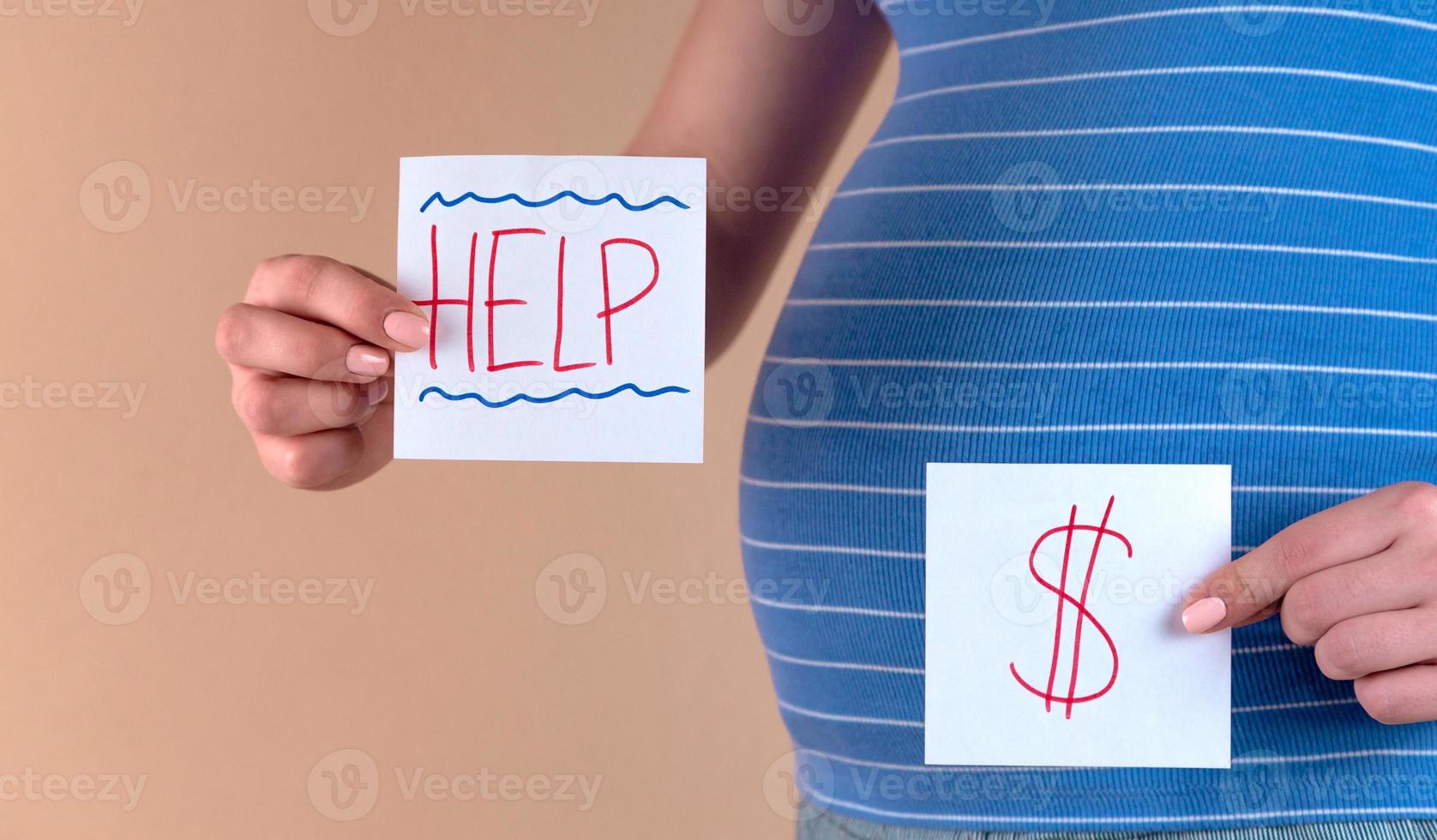 eine Nahaufnahme des Bauches einer schwangeren Frau mit den Worten Hilfe und einem Dollarzeichen foto
