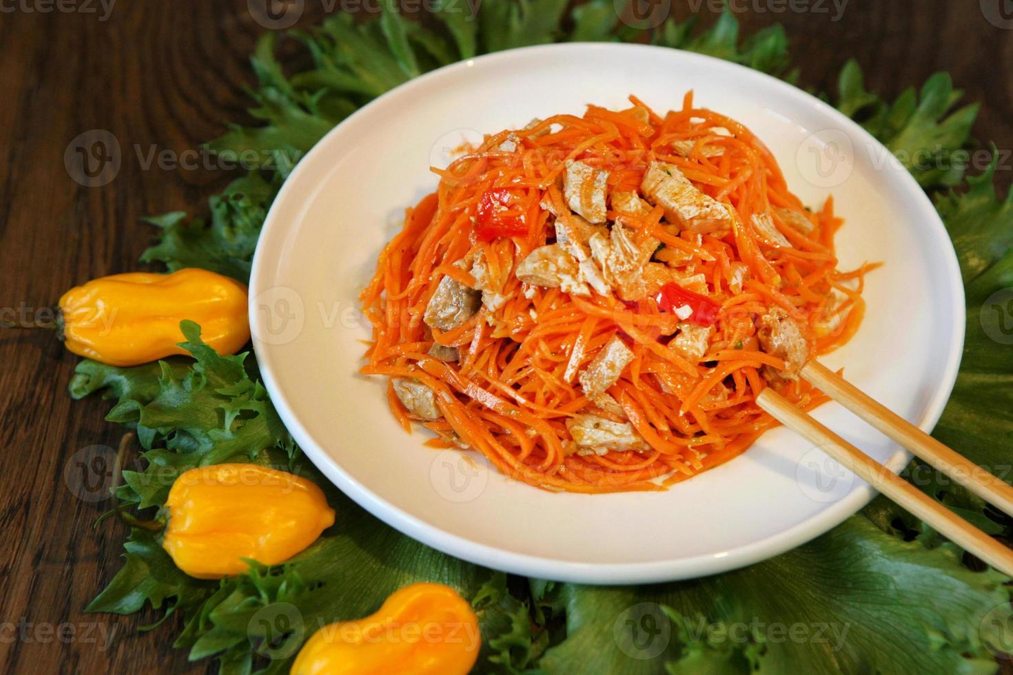 koreanischer Karottensalat mit Essstäbchen auf hölzernem Eichentisch foto