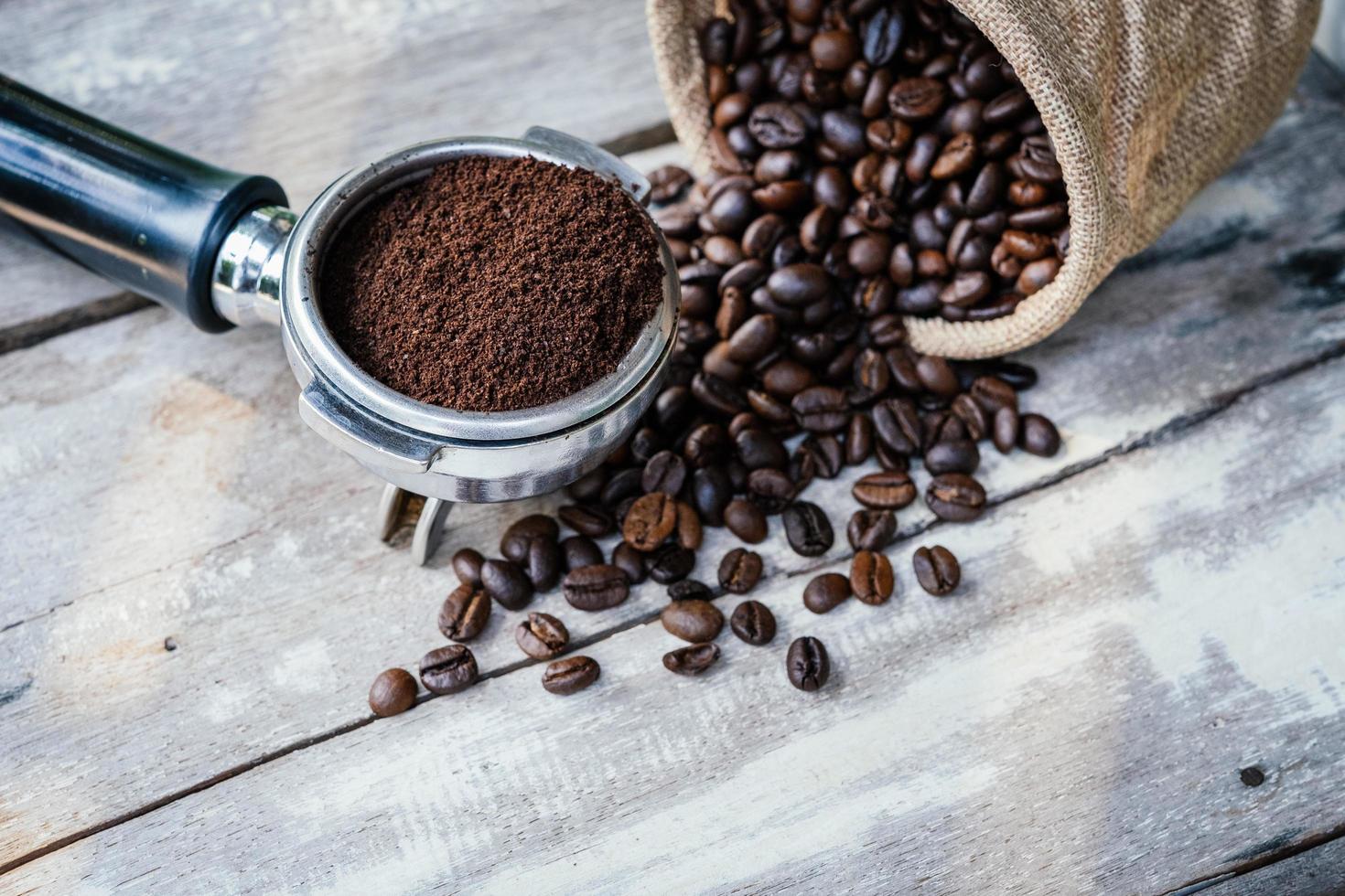 Kaffeebohnen in Sack und Siebträger auf altem weißem Holztisch foto