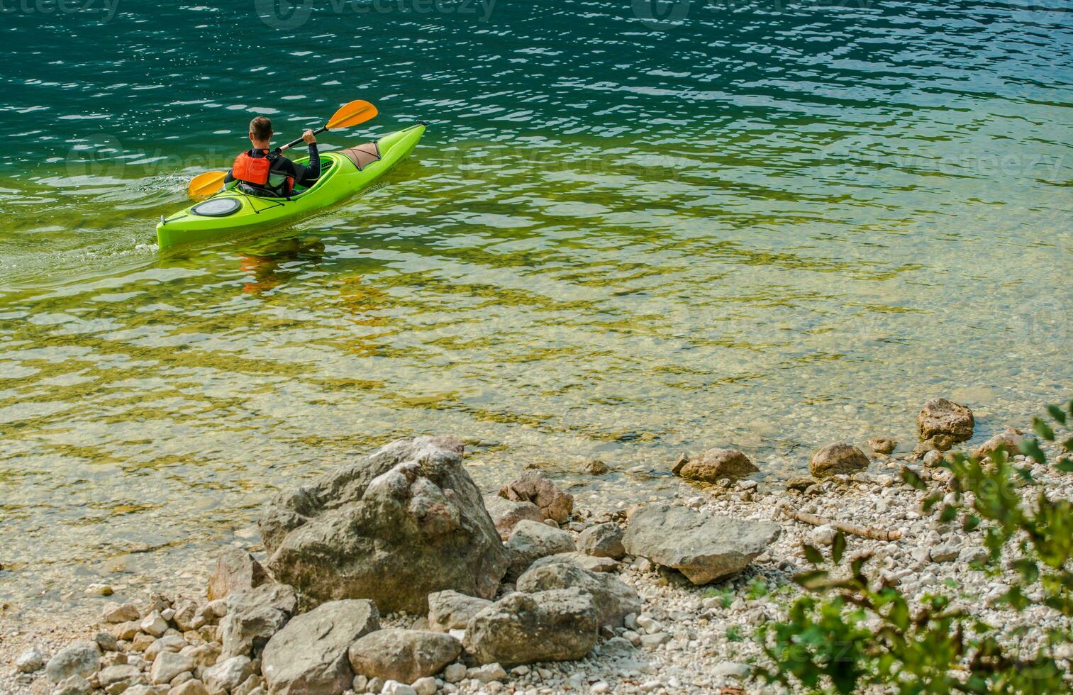 kaukasisch männlich Kajak fahren im klar Wasser von See. foto