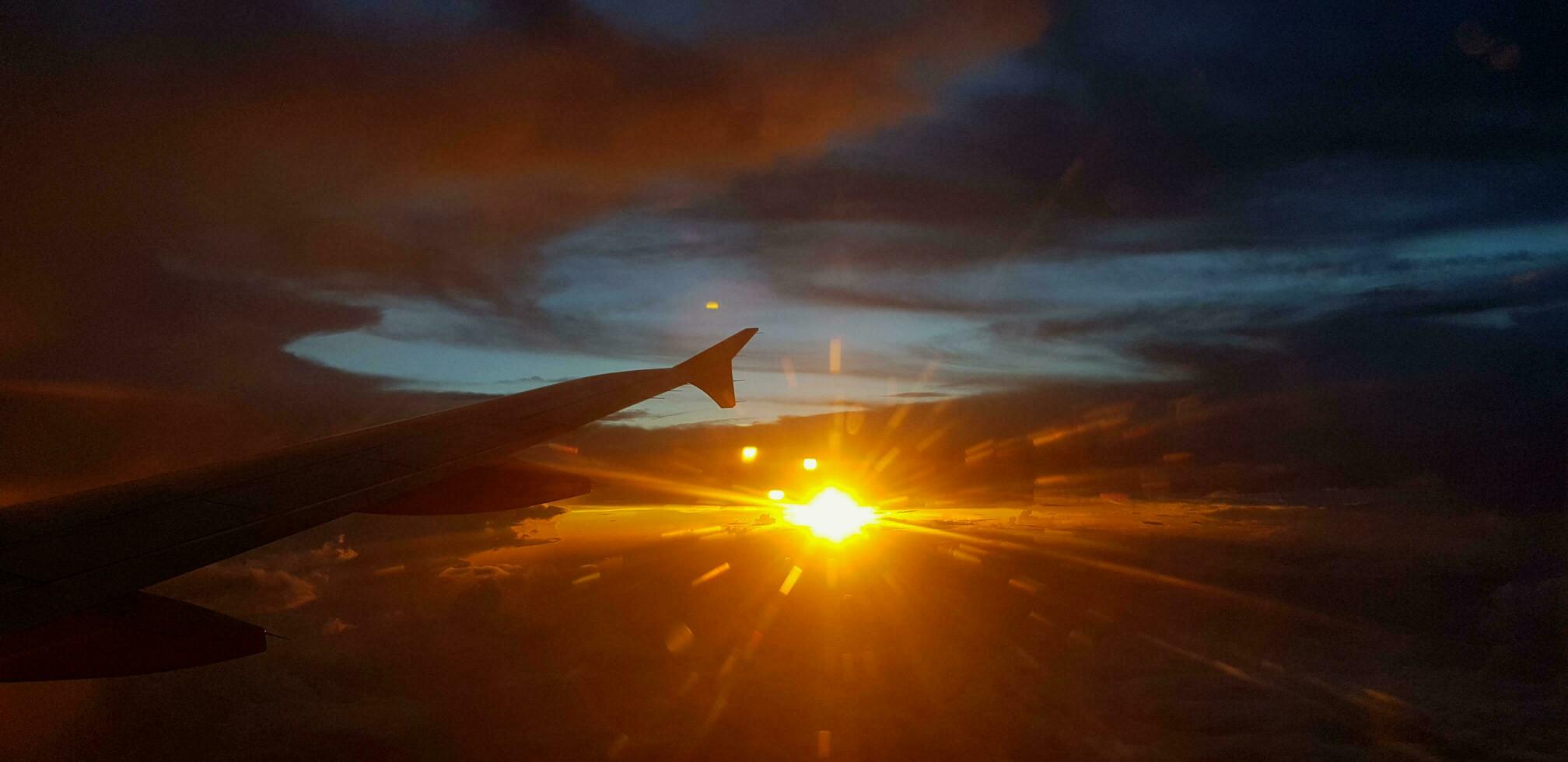 Silhouette von Flugzeug oder Flugzeug Flügel auf dunkel Himmel mit Sonnenuntergang Licht Fackel Hintergrund. Transport, Reise und Schönheit von Natur Konzept foto