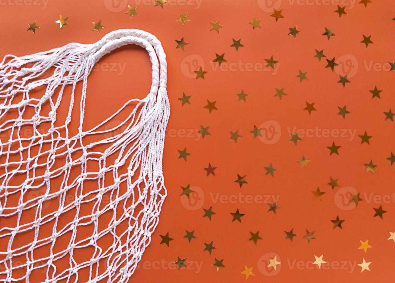 weiße Schnur Baumwolle Öko-Tasche auf orange Hintergrund mit Goldsternen Dekoration einfache flache Lage mit Kopie Raum Ökologie Null Abfall Konzept Lager Fotografie foto