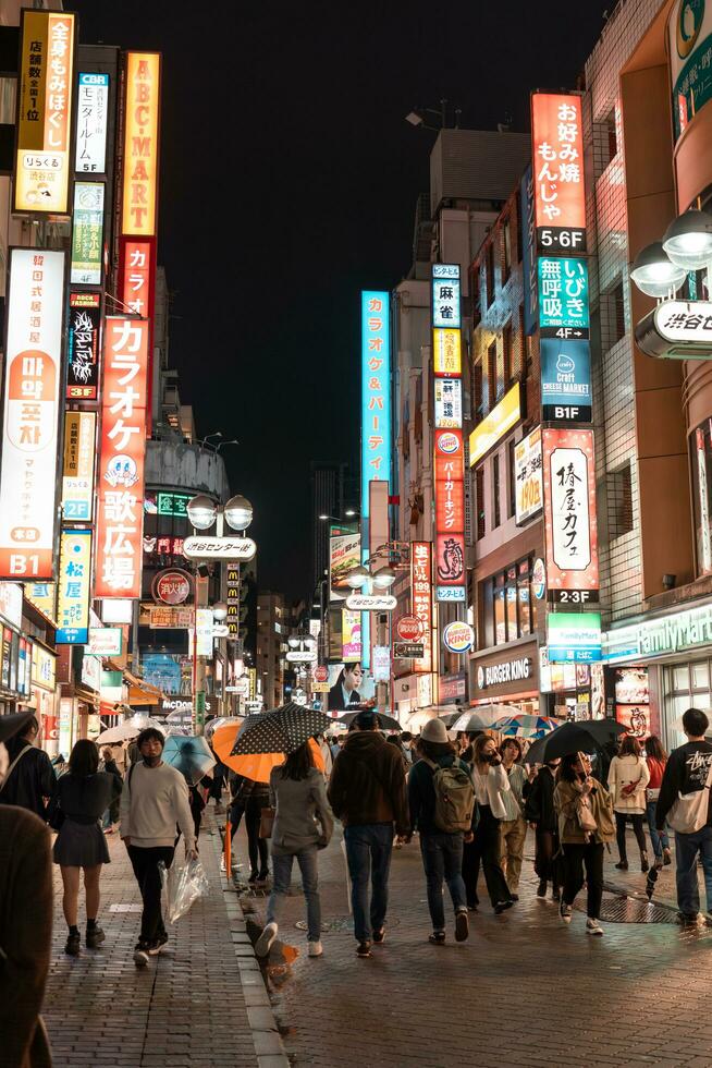 Tokio, Japan - - April 8, 2023 Menschen Gehen im Shibuya Einkaufen Bereich im Nieselregen Abend foto