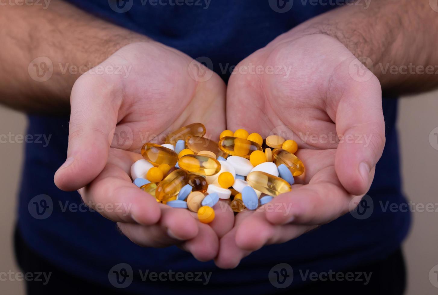 ein Haufen mehrfarbiger Pillen in männlichen Händen foto