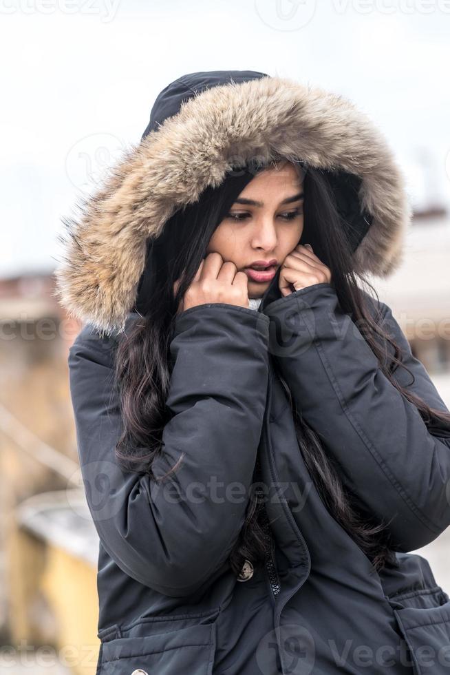 süße junge Frau, die im Wintermantel einfriert, der im Straßenwinterporträt steht foto