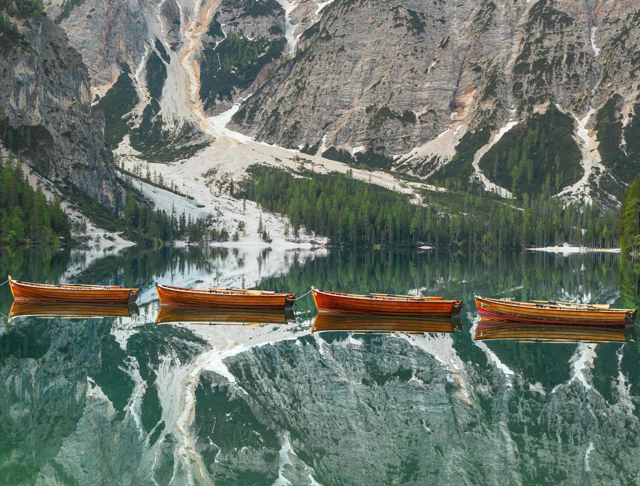 Holzboote spiegeln sich im klaren, ruhigen Wasser des pragser wildsee lago di braies in dolomites unesco welterbe südtyrol italien foto