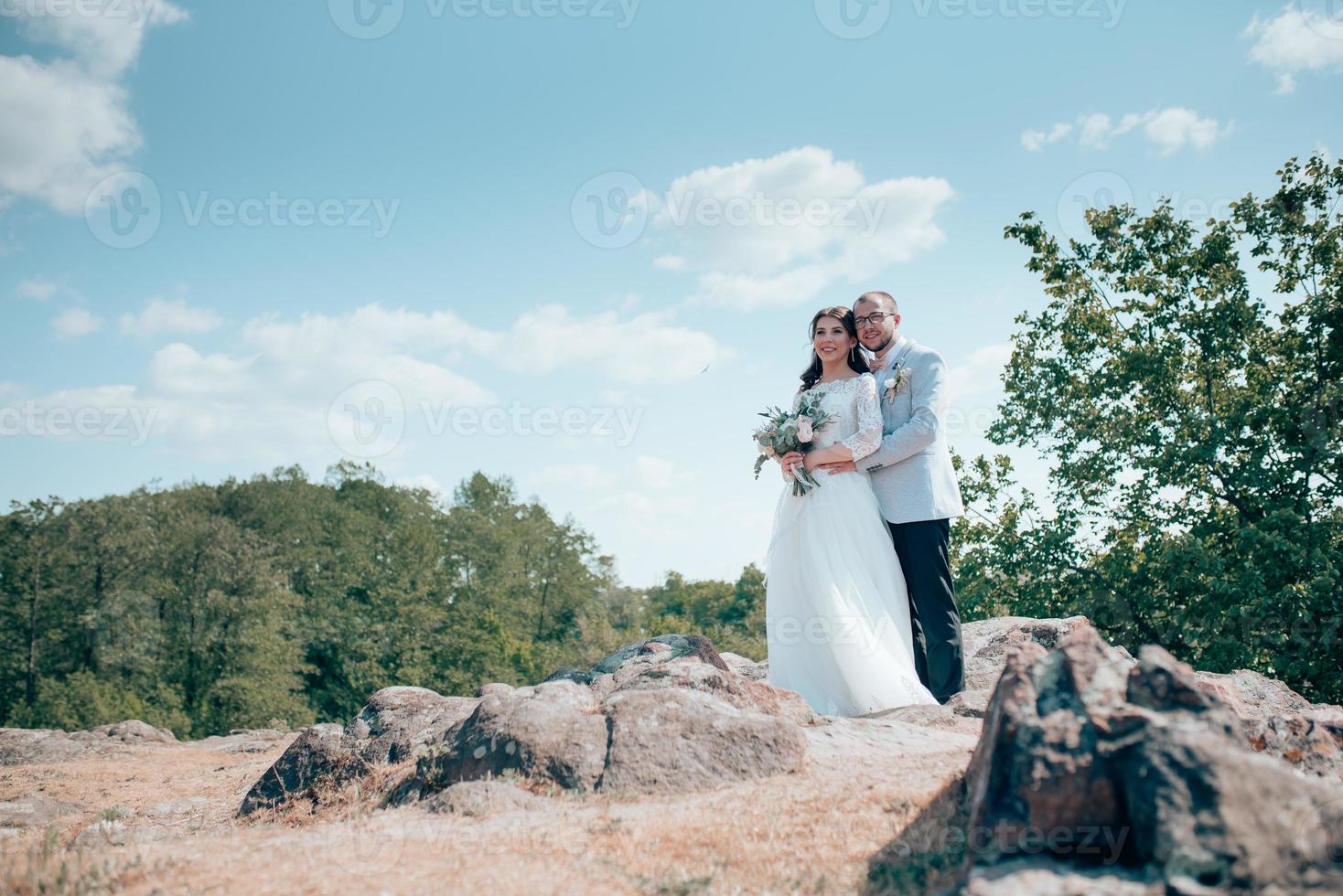 Hochzeitsfoto der Braut und des Bräutigams in einer grau rosa Farbe auf Natur im Wald und in den Felsen foto