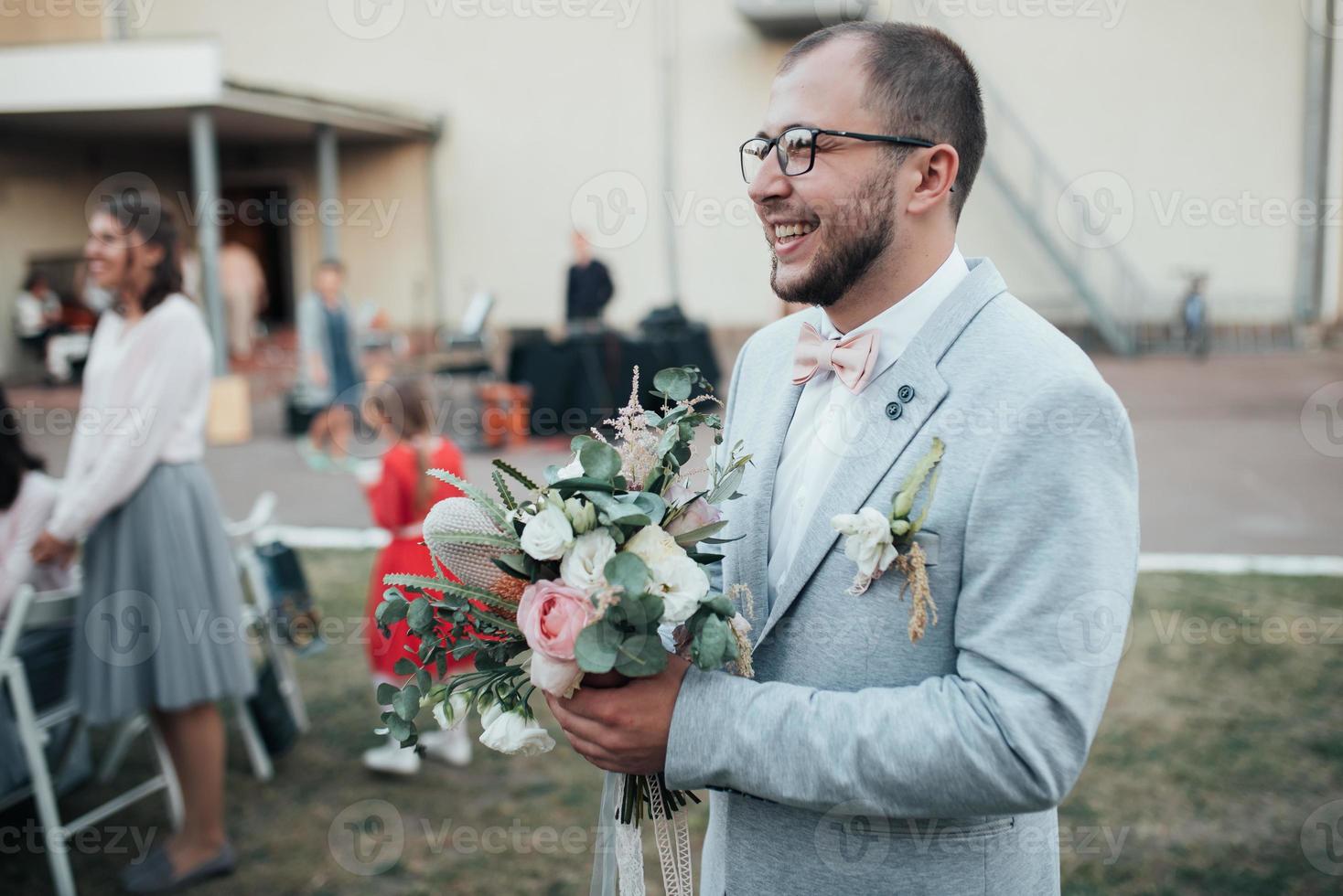 Hochzeitsfoto der Gefühle eines bärtigen Bräutigams mit Brille in einer grauen Jacke und im rustikalen Stil foto