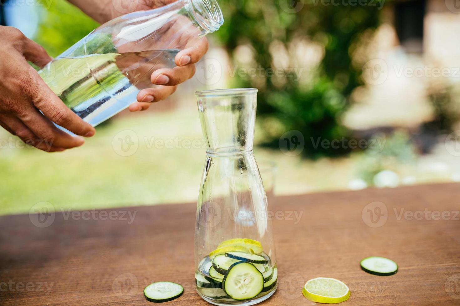 Wasser mit Gurke in die Flasche gießen foto