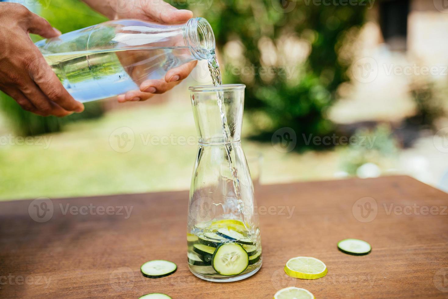 Wasser mit Gurke in die Flasche gießen foto