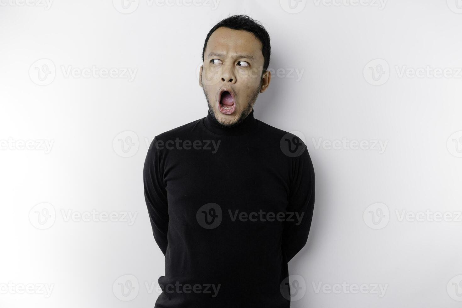 schockiert asiatisch Mann mit seine Mund breit öffnen tragen schwarz Shirt, isoliert durch ein Weiß Hintergrund foto