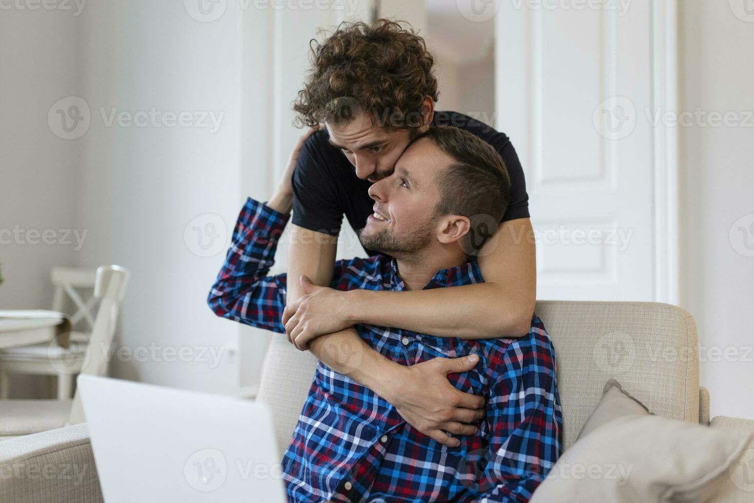 schön Fröhlich Paar Lachen zusammen während Sitzung im ihr Leben Zimmer beim heim. zwei romantisch jung männlich Liebhaber haben Spaß Surfen das Internet drinnen. jung Fröhlich Paar Leben zusammen. foto