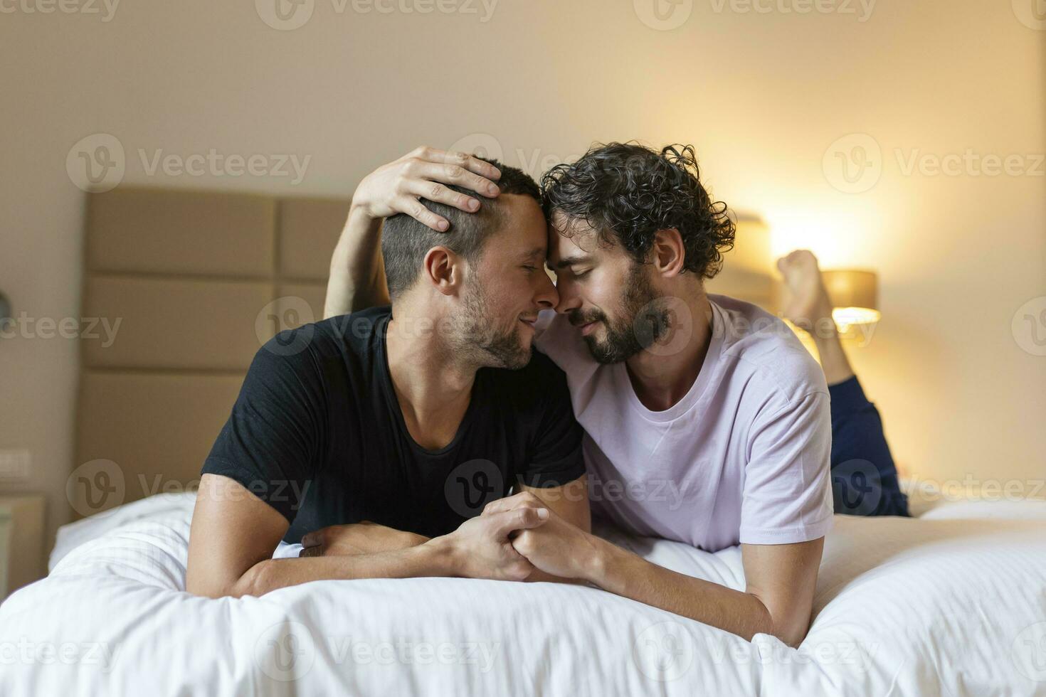 glücklich Fröhlich Paar Lügen Nieder auf das Bett beim heim, umarmen und flirten. lgbt Fröhlich Paar Liebe Momente Glück Konzept foto