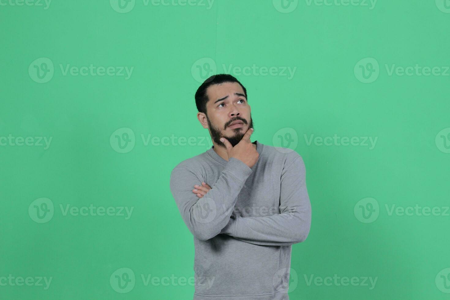 bärtig asiatisch Mann posiert tragen ein grau Hemd gegen ein Grün Hintergrund foto