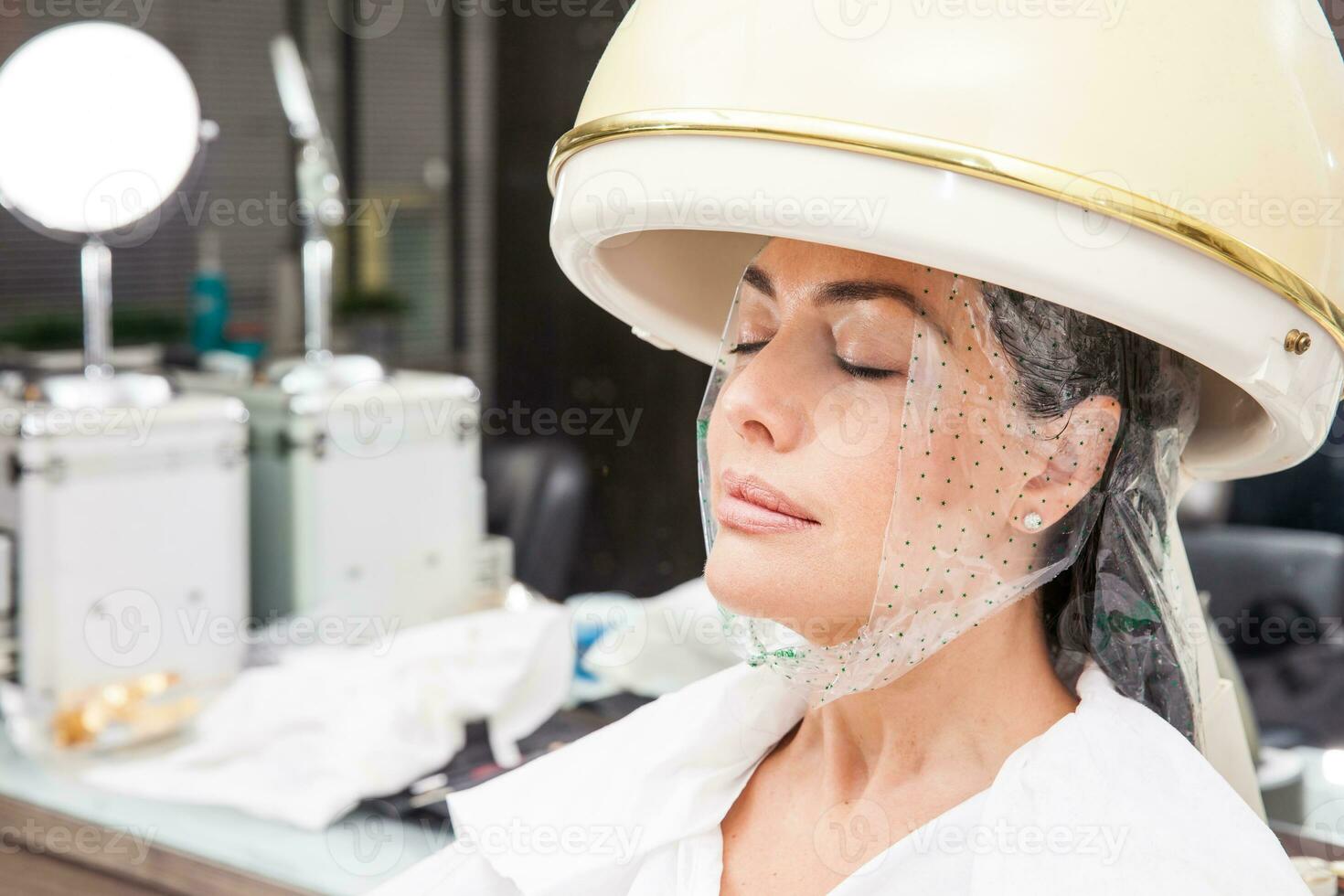 Frau unter ein Fachmann Haar Dampfer mit ein Haar Behandlung foto