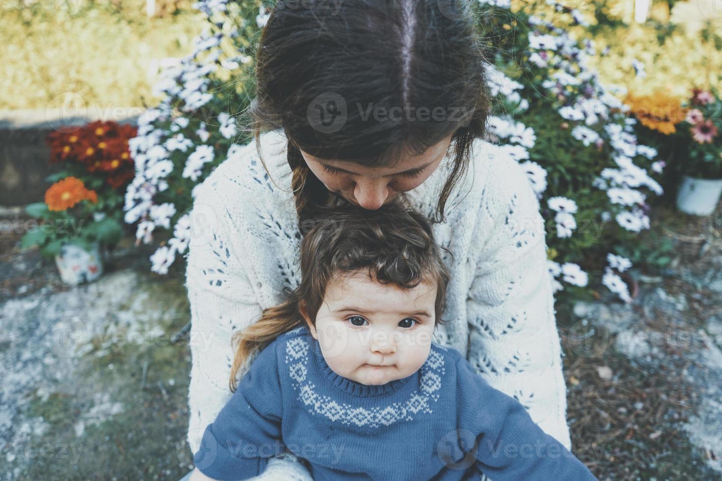 junge Mutter umarmt ihr Baby und genießt einen Frühlingstag im Garten foto