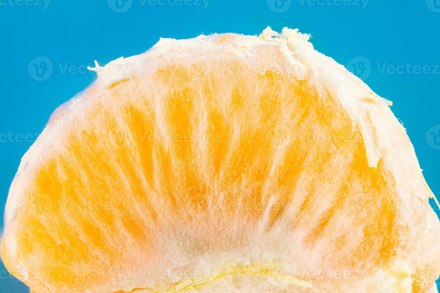 Scheibe der einzelnen frischen Mandarine auf blauem Hintergrund foto