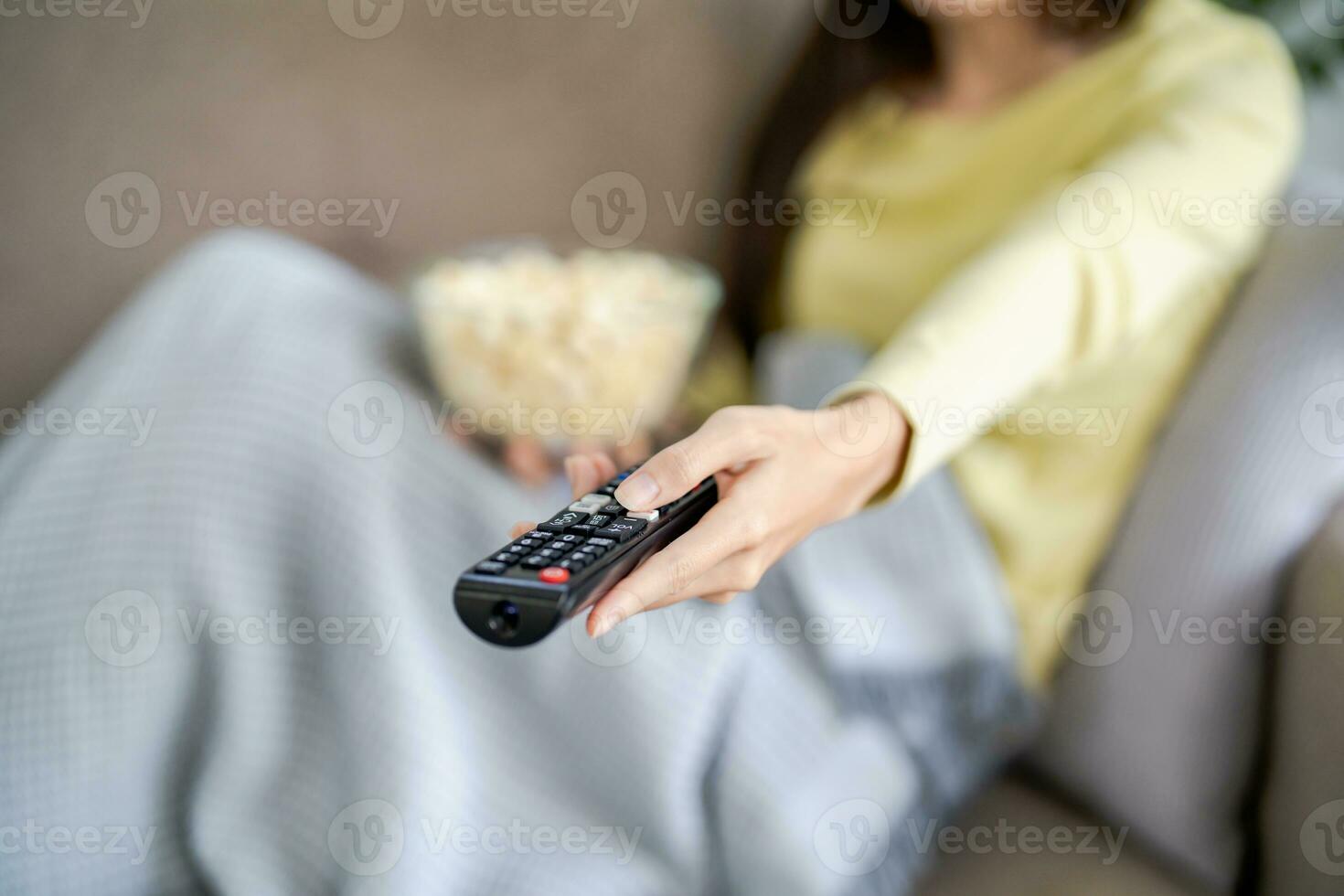asiatisch Frau Aufpassen Clever Fernseher und mit Fernbedienung Regler Hand halten Fernsehen Audio- Fernbedienung Steuerung beim Zuhause mit das Fernbedienung Steuerung Fernsehen foto