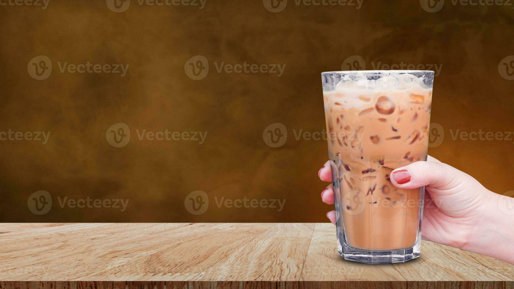 Hand halten das Glas vereist Kaffee auf hölzern Tabelle auf abstrakt dunkel Hintergrund, Eis Latté Kaffee foto