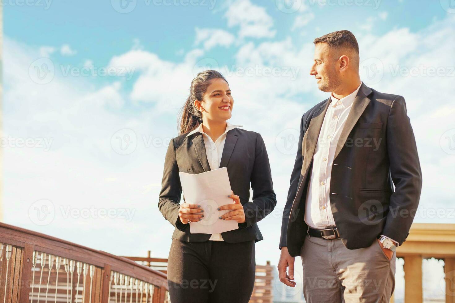 zwei indisch Kollegen im Formale Gehen draußen während diskutieren das dokumentieren foto