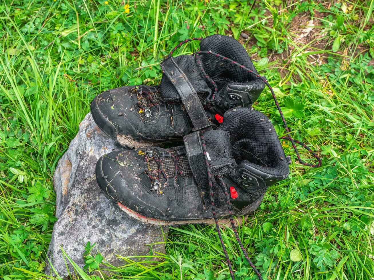 nass schwarz Wandern Stiefel trocken auf ein Stein gegen das Hintergrund von Grün Gras. Schwierigkeiten von wandern, Trocknen Kleider im Natur. foto