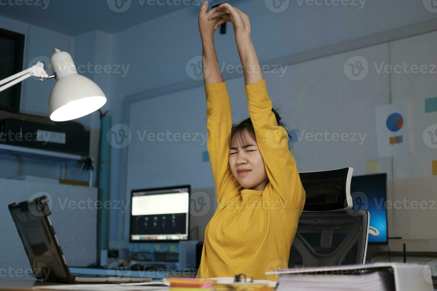 Frau Verdrehen das Körper zu entspannen während Sitzung wie sie sitzt beim ihr Schreibtisch nach Arbeiten alle Tag. foto