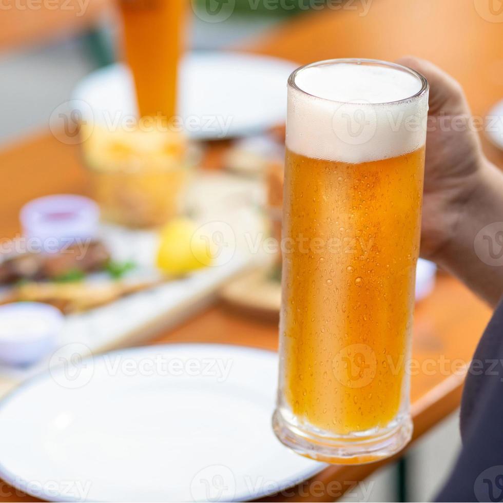 Mann hält Bierkrug mit Snacks auf dem Tisch foto