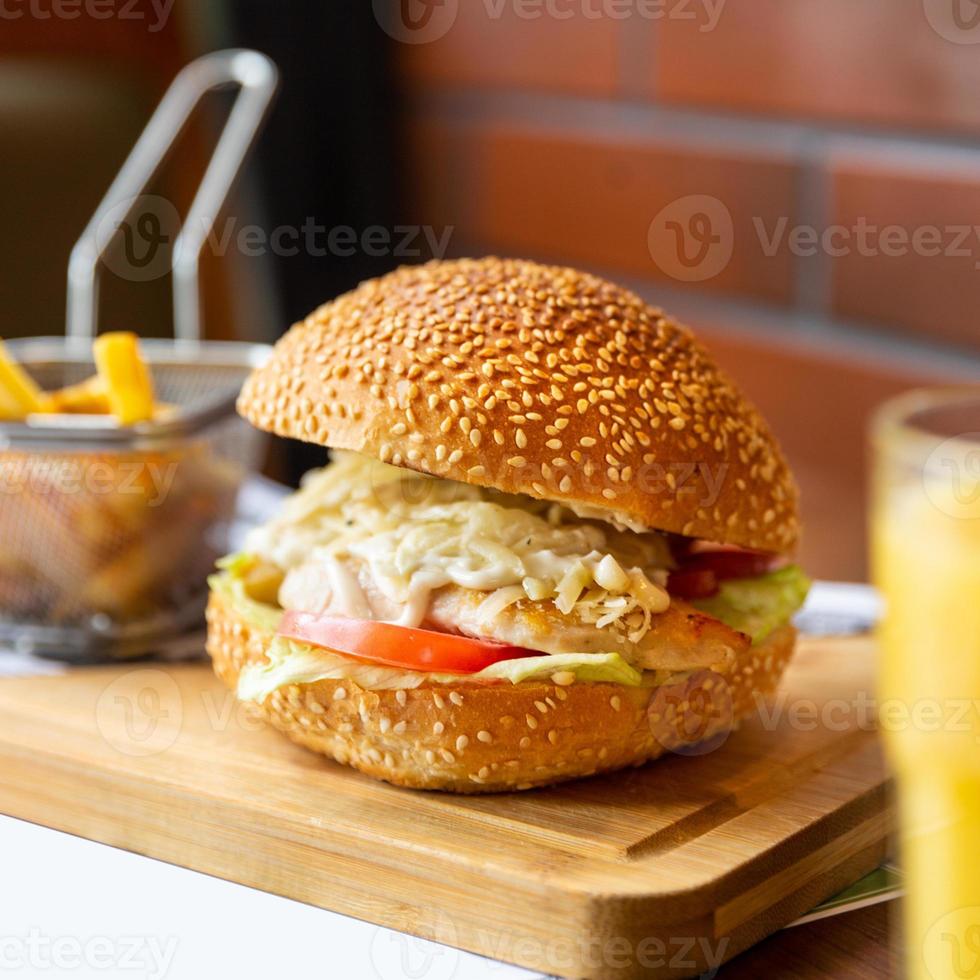 Caesar Burger mit Pommes auf dem Holzteller foto