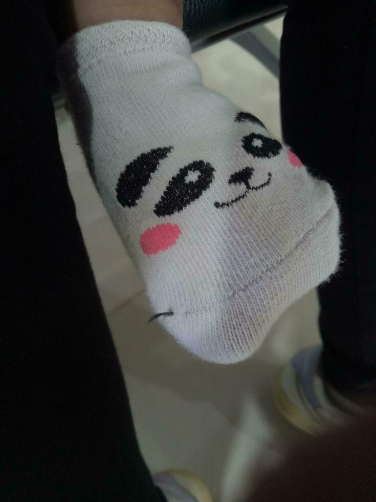 Foto von ein Babys Fuß im ein Socke mit ein süß Panda Gesicht auf es