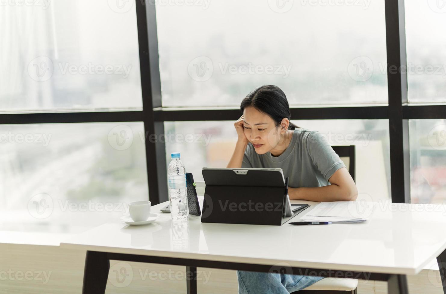 schöner lächelnder Frauenvideoanruf auf Handy während während der Arbeit am Laptop foto