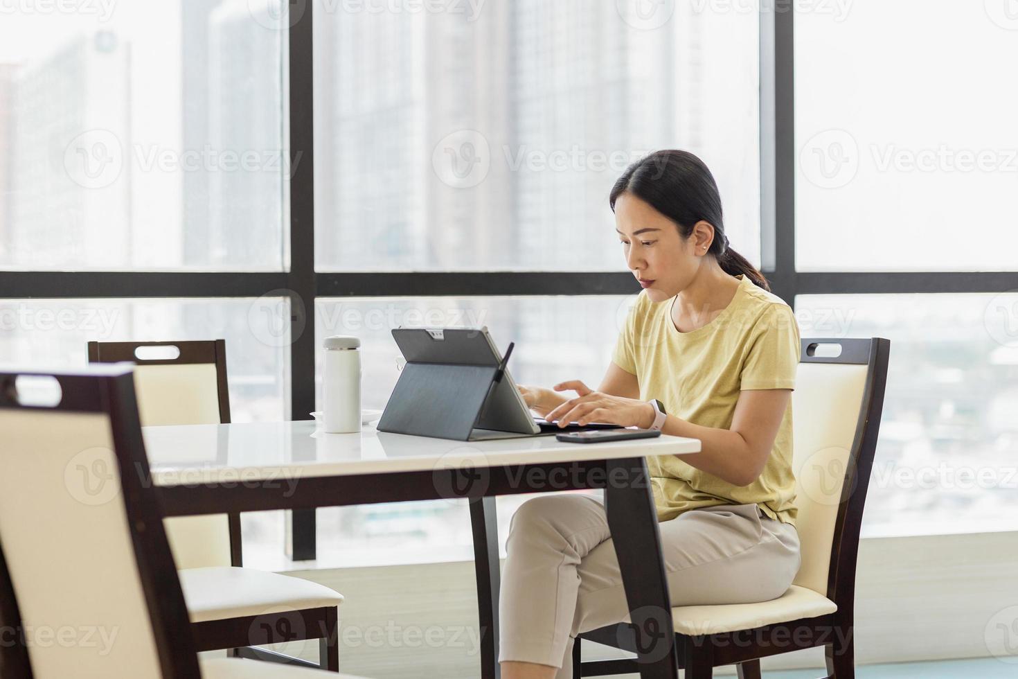 konzentrierte freiberufliche Frau, die zu Hause am Laptop arbeitet foto