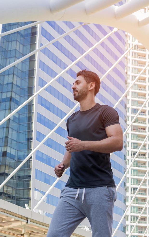 hübsche Männer, die Sportkleidung tragen und draußen in der Stadt laufen foto