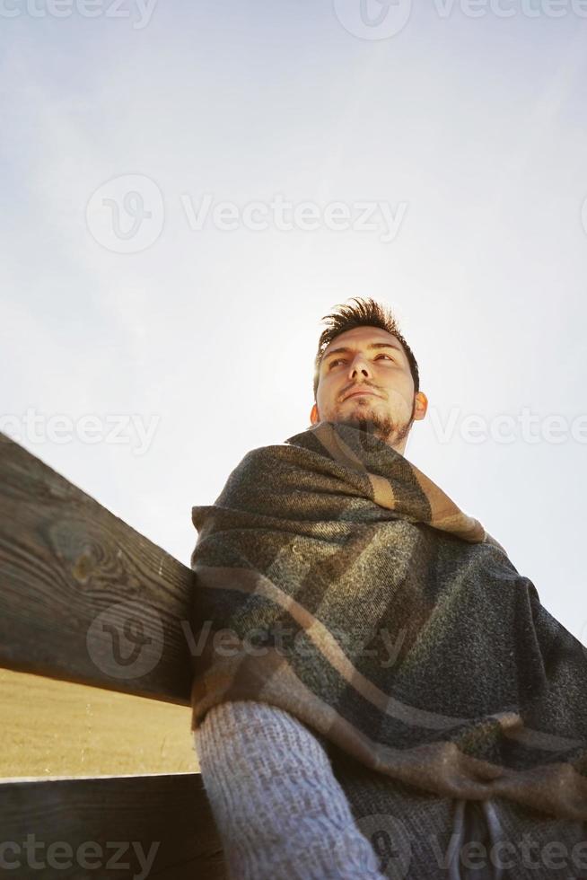 junger Mann, der die ruhige Morgenherbstsonne mit der Hintergrundbeleuchtung genießt, die vom blauen Himmel leuchtet foto