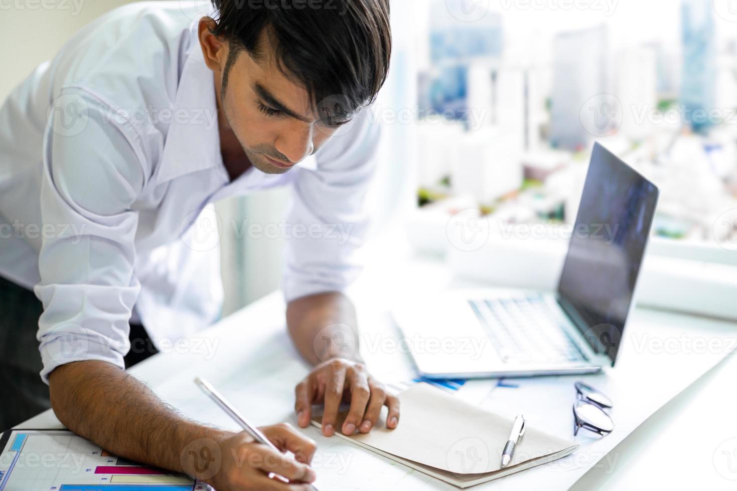 Geschäftsmann, der mit Laptop und Dokumenten arbeitet foto