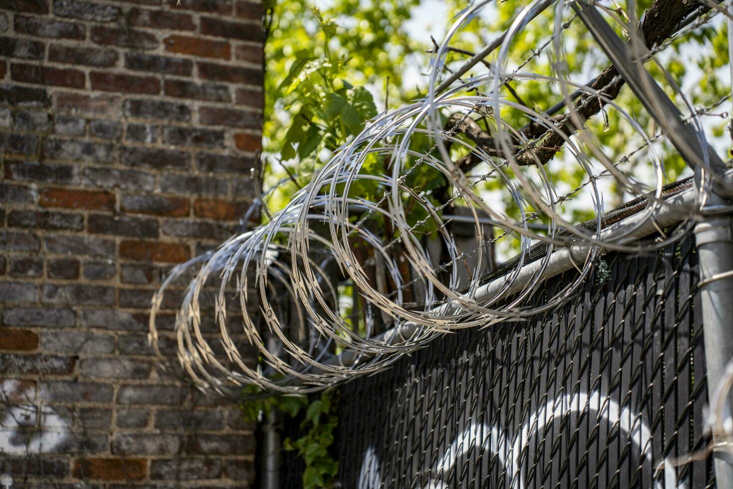 mit Widerhaken Draht auf ein Zaun Nächster zu ein Backstein Mauer foto