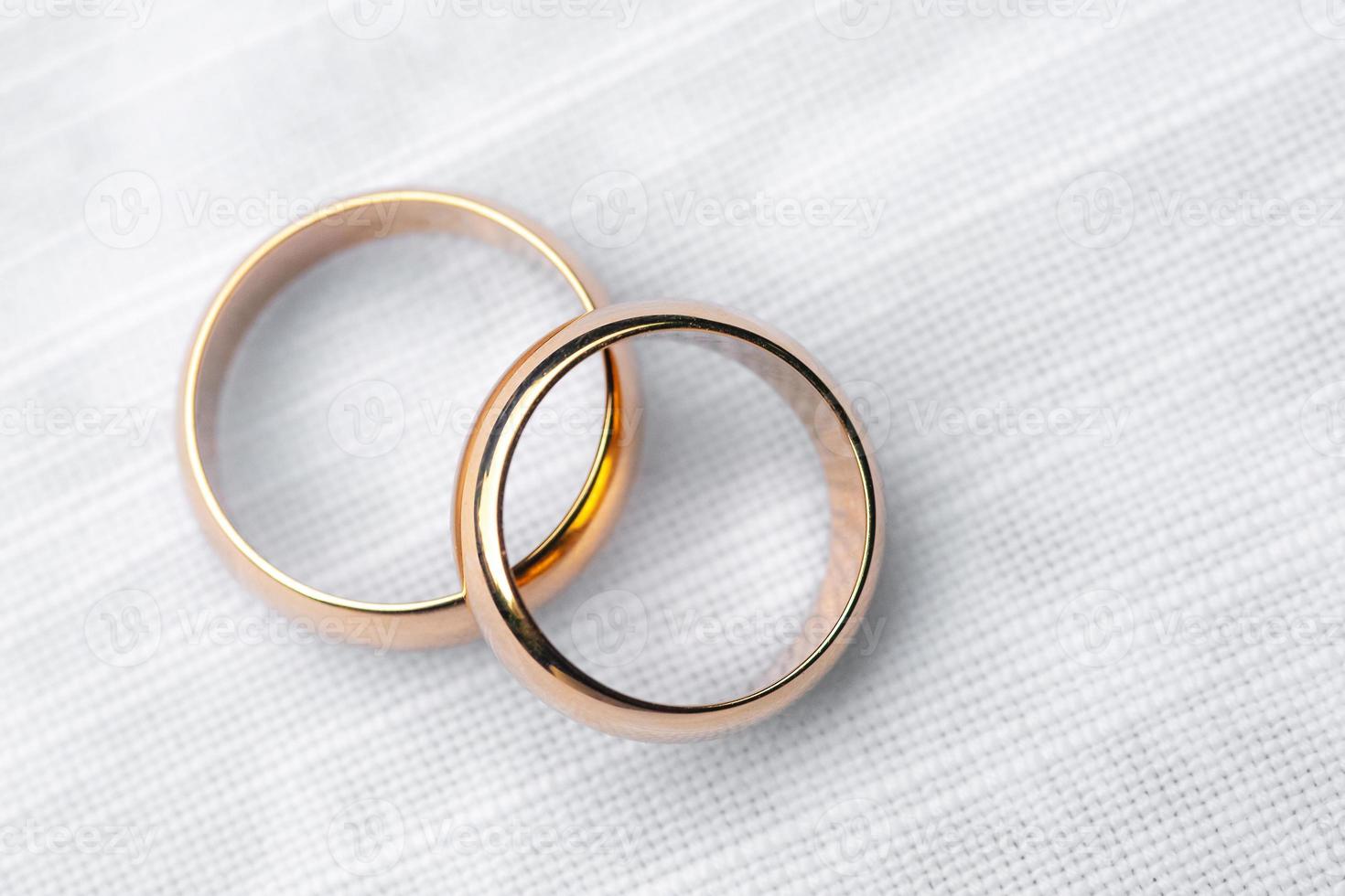 zwei goldene Ringe auf weißer Tischdecke foto