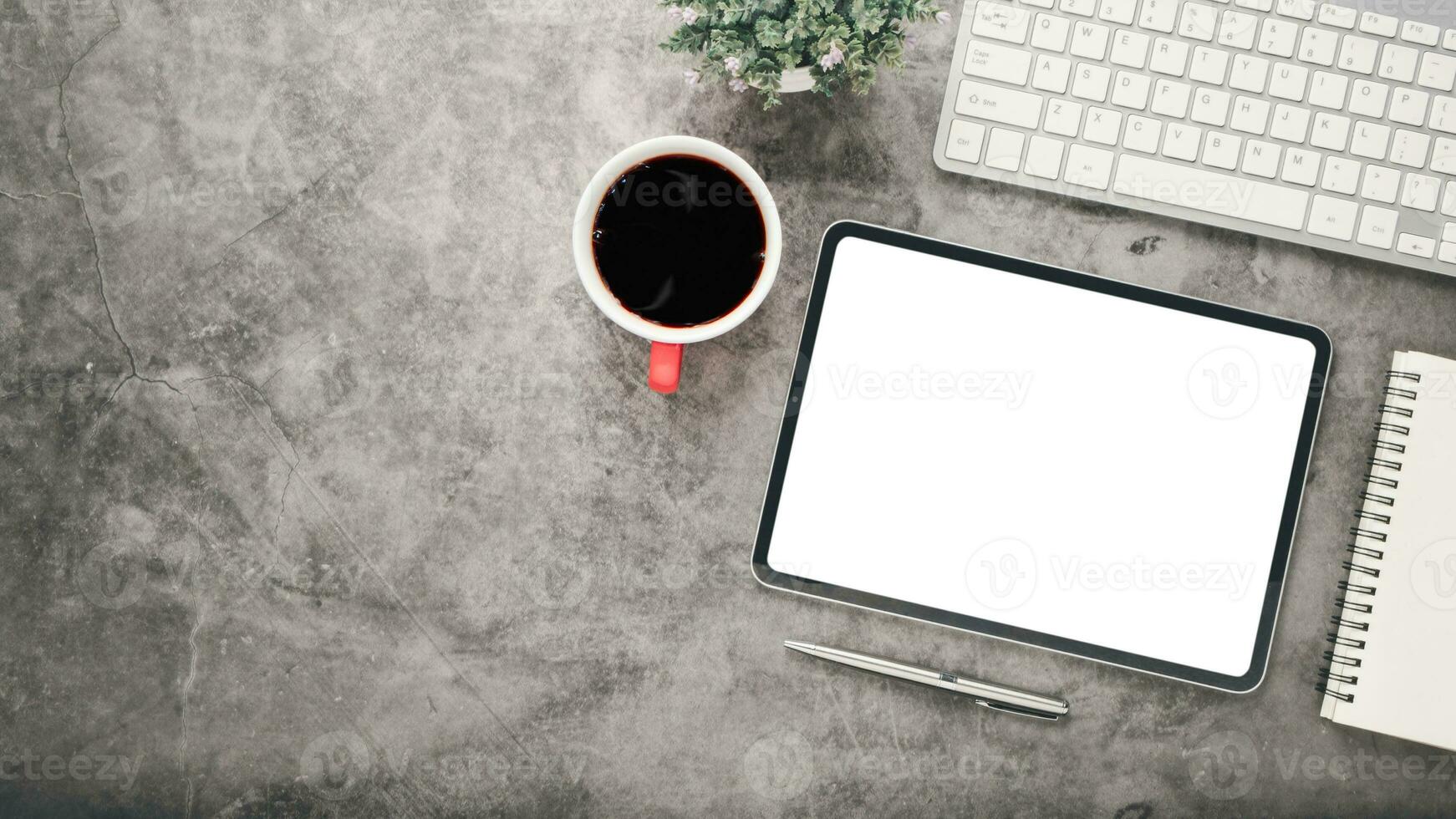 Büro Schreibtisch Arbeitsplatz mit leer Bildschirm Tablette, Stift, Notizbuch, Tastatur und Tasse von Kaffee, oben Aussicht eben legen mit Kopieren Raum. foto